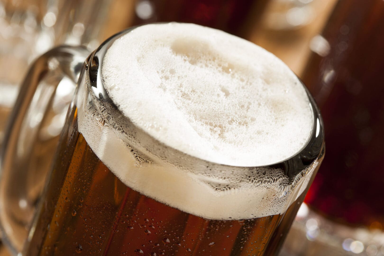 Close-up of a frothy mug of beer with condensation on the glass.