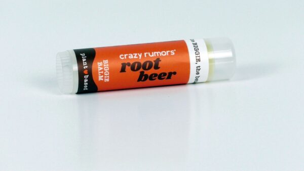 The Root Beer Biggie Lip Balm, reminiscent of a nostalgic trip to a beer museum, features an orange label with black accents set against a white background.