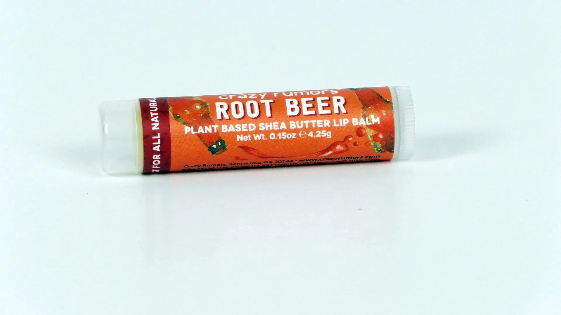 Root Beer Regular Lip Balm, a plant-based shea butter lip balm inspired by the nostalgic experience of visiting a beer museum, is packaged in a convenient small tube on a white background.