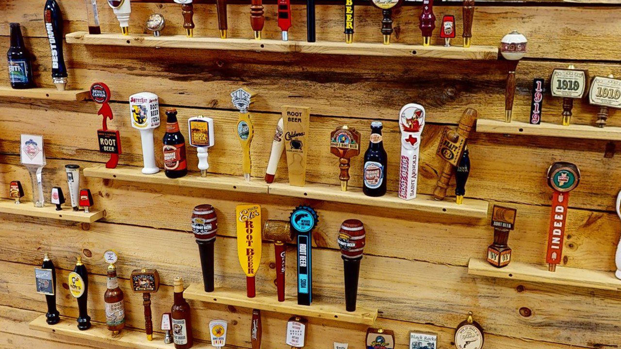 A wooden display wall with various beer taps and beer-themed memorabilia arranged on shelves.