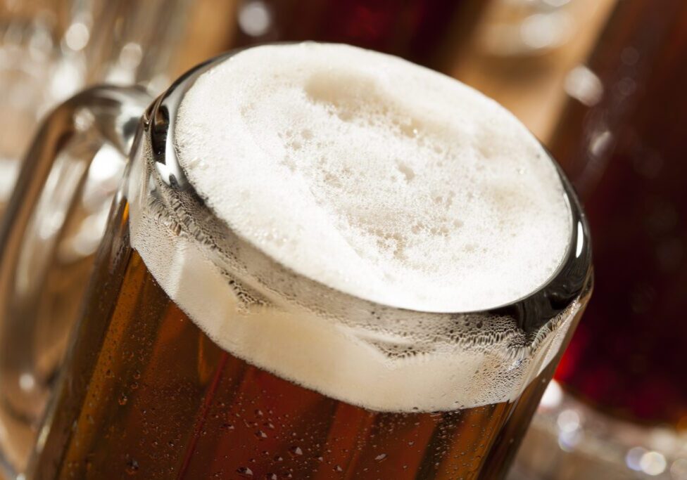 Close-up of a frothy mug of beer with condensation on the glass.